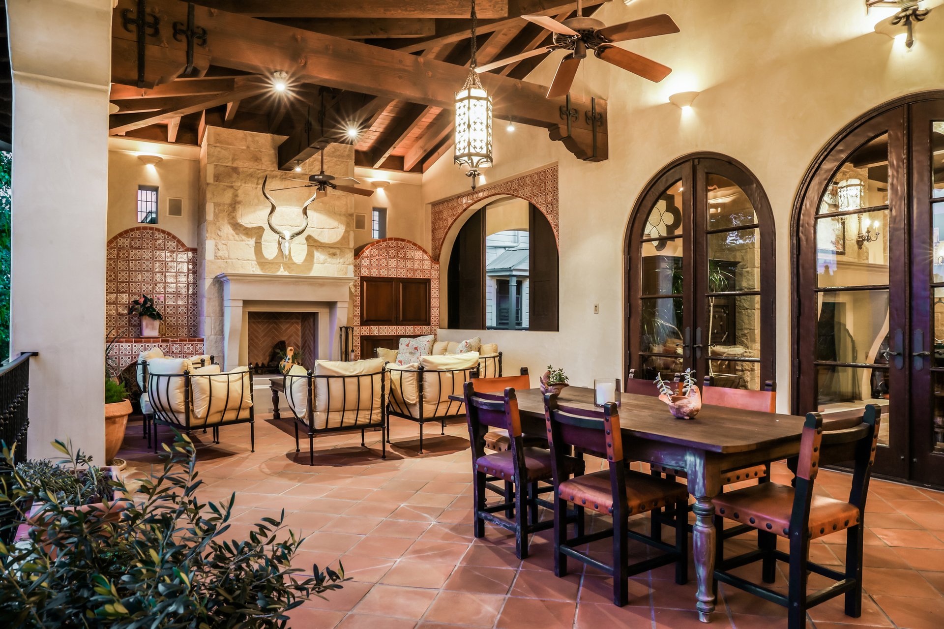 Outdoor loggia with stone fireplace, wood-beamed ceiling, and terracotta floors