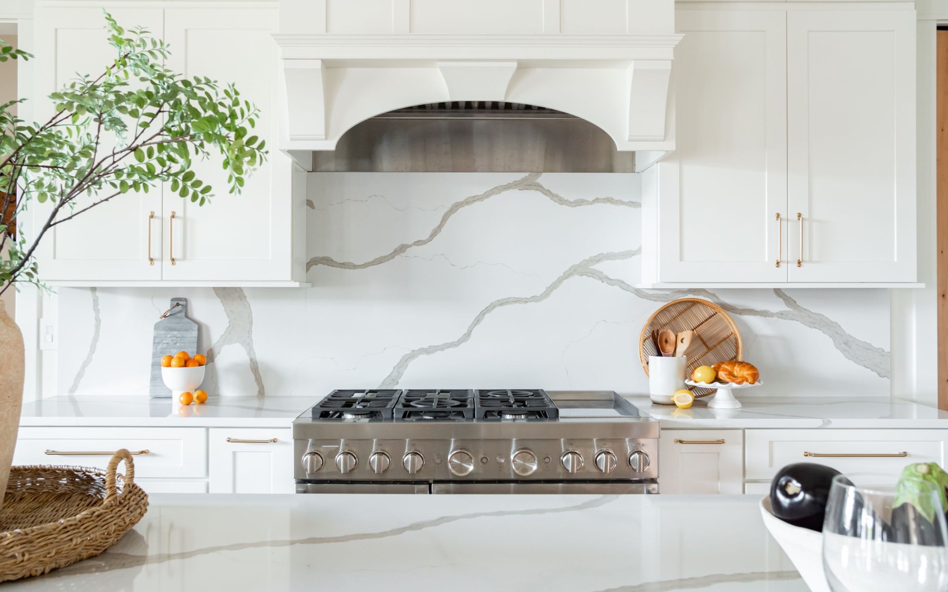 Chef's kitchen with marble backsplash, professional range, and white cabinetry
