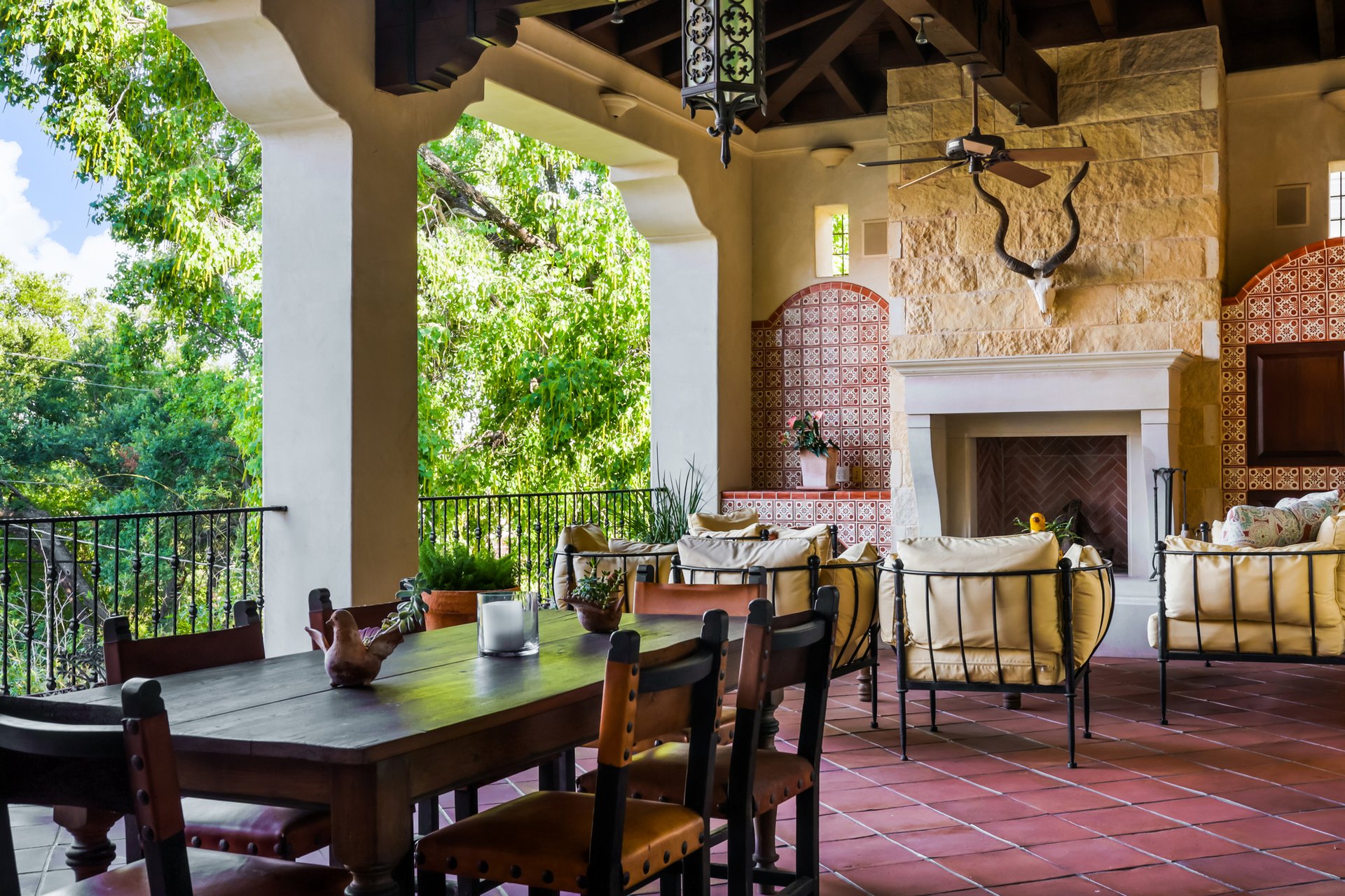 Covered terrace overlooking the trees with stone fireplace and patterned tile