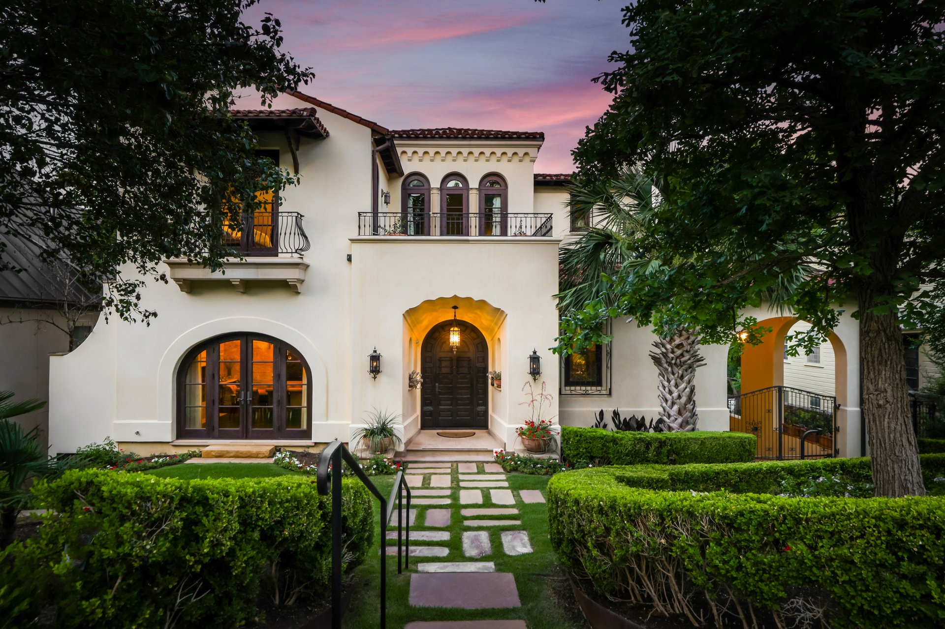 2303 Windsor Road, Austin, Texas — Mediterranean residence at dusk with arched doorway and second-floor balcony